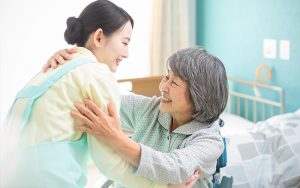 介護職員と入居者のふれあい。ベッドサイドでのケアシーン。