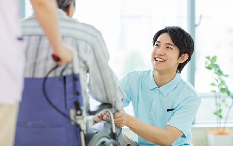 介護職員が入居者と車椅子で笑顔で会話している日常風景